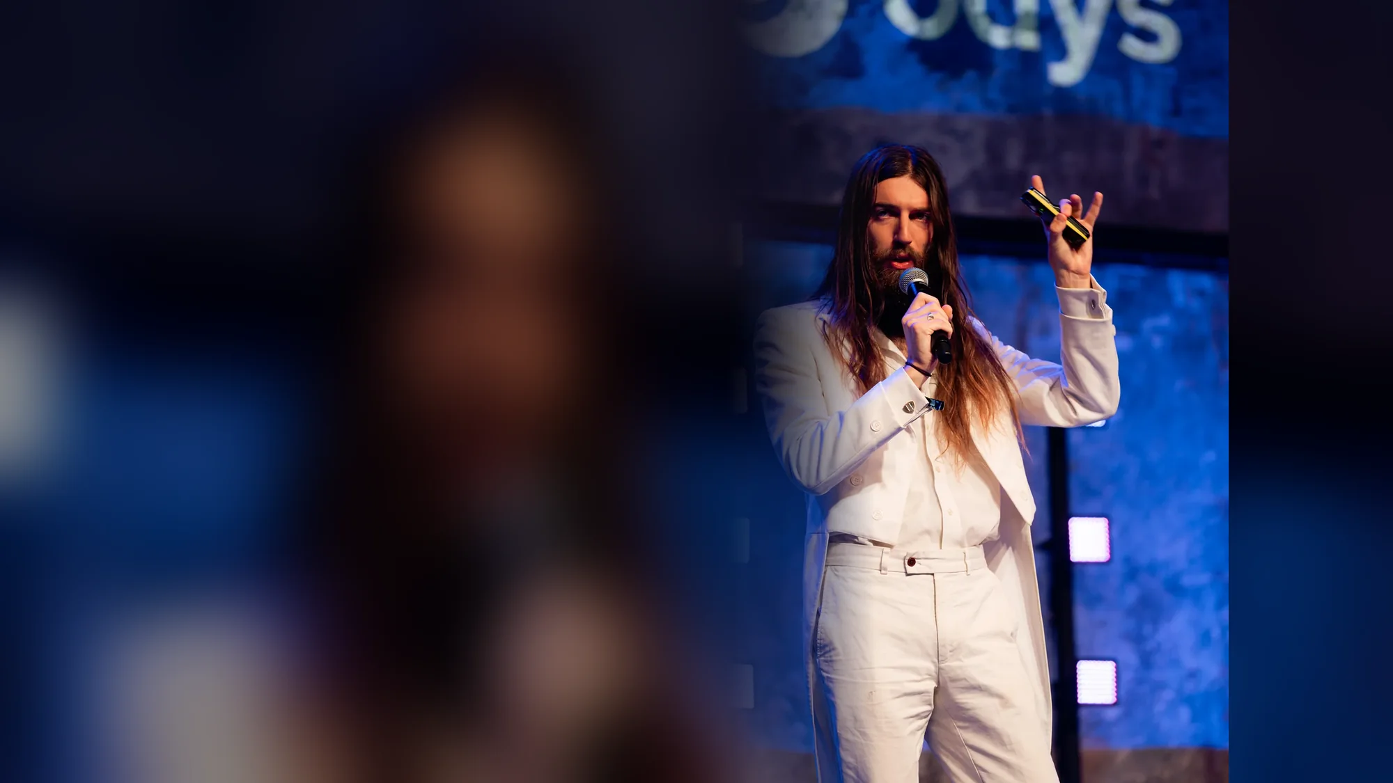 Stewart Vickers speaking on stage in a white suit at SEO Estonia, Tallinn