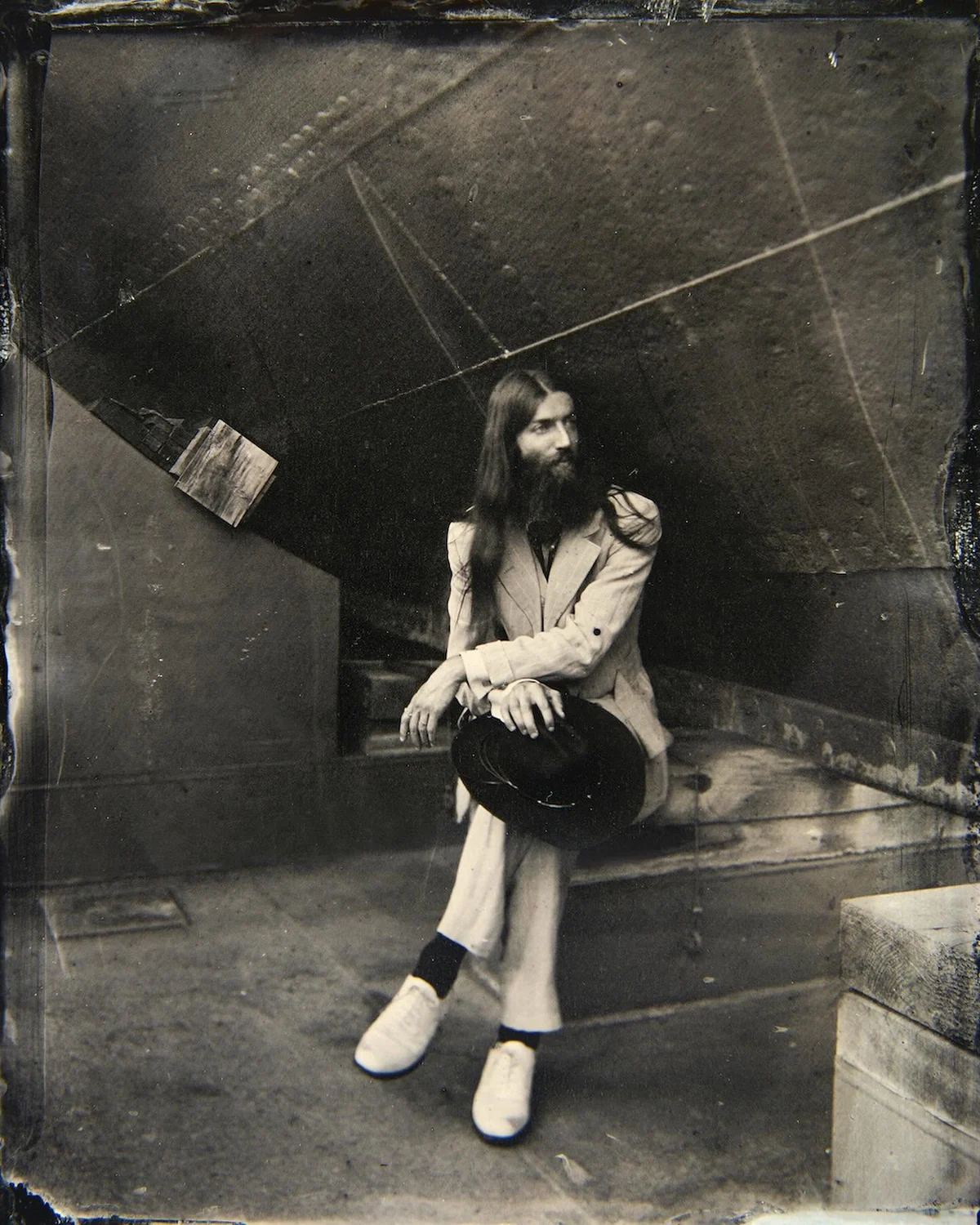 Wet-collodion tintype of a seated figure, the plate's pour marks visible across the top