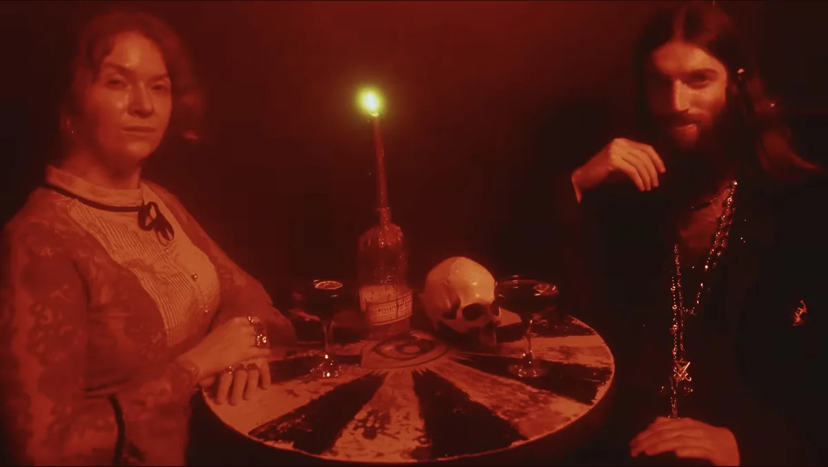 Red-lit frame from the Green Lung video Maxine (Witch Queen), two figures at a ritual table