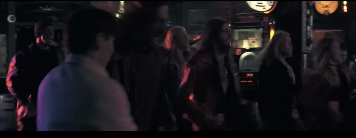Frame from Skindred, Machine: a dim bar crowd beside a lit jukebox