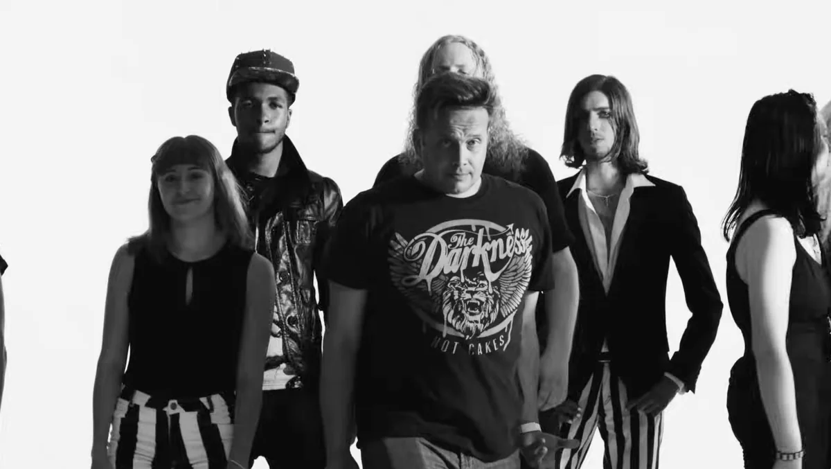 Black and white frame from The Darkness, Last of Our Kind: fans lined up against a white background