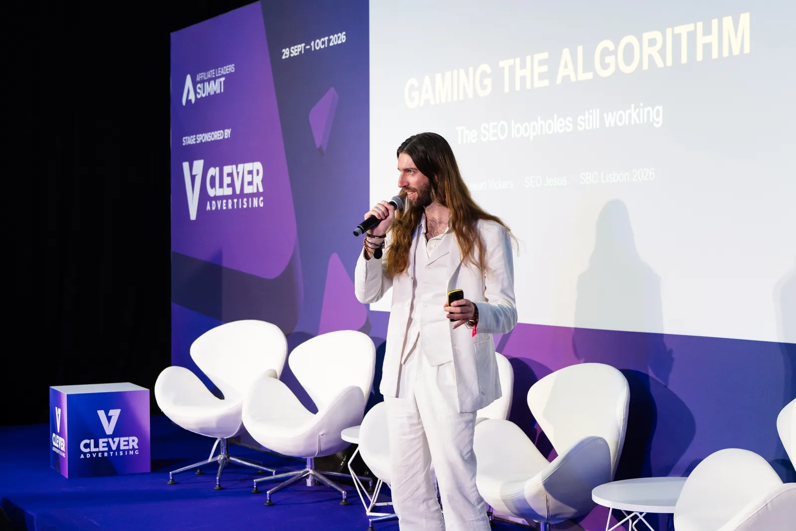 Stewart Vickers on stage at SBC Summit Lisbon 2026, his title slide Gaming the Algorithm: The SEO Loopholes Still Working projected behind him